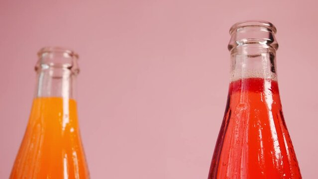 Closeup footage of a hand taking an orange lemonade bottle from three colorful bottles