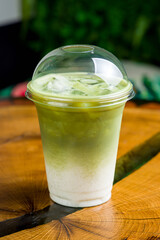 ice green matcha tea on glass on wooden table, cold, vertical