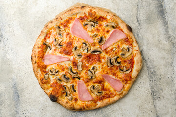 Pizza with ham and mushrooms with cheese and tomato sauce on stone table top view