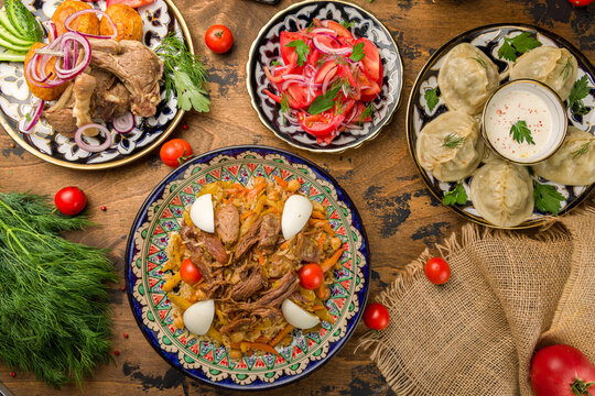 Pilaf festivities with beef, manti with beef,kazan kebab with lamb, salad tomatoes with red onion achik chuchuk top view on wooden table