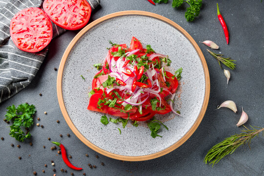 Tomato salad with red onion on plate, achichuk salad, achik chuchuk top view