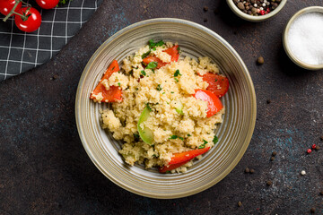 couscous with vegetables on bowl top view on dark stone table