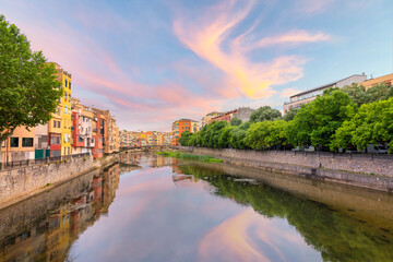 Fototapeta premium The Spanish town of Girona bathed in colorful light at sunset on the River Onyar, in the Catalonian Costa Brava region of Southern Spain.