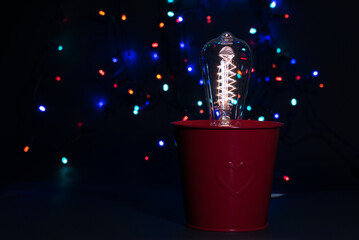 red pot with Edison light bulb on dark background with colorfull lights - Powered by Adobe