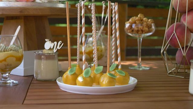 Peach cakepops on decorated table prepared for birthday celebration. Delicious cake-pops turned upside down on plate with colorful decoration.