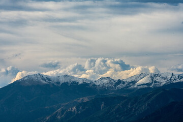 Fototapeta na wymiar Clouds Brew Over Snow Capped Mountains in Colorado