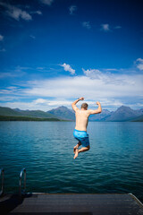 man jumping into a mountain lake
