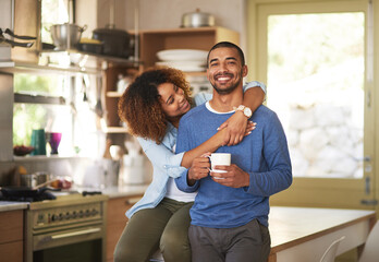 Black couple relaxing, drinking coffee and looking happy together in the kitchen in the morning at home. Portrait of a young, cheerful and loving husband and wife enjoying romantic time on weekend