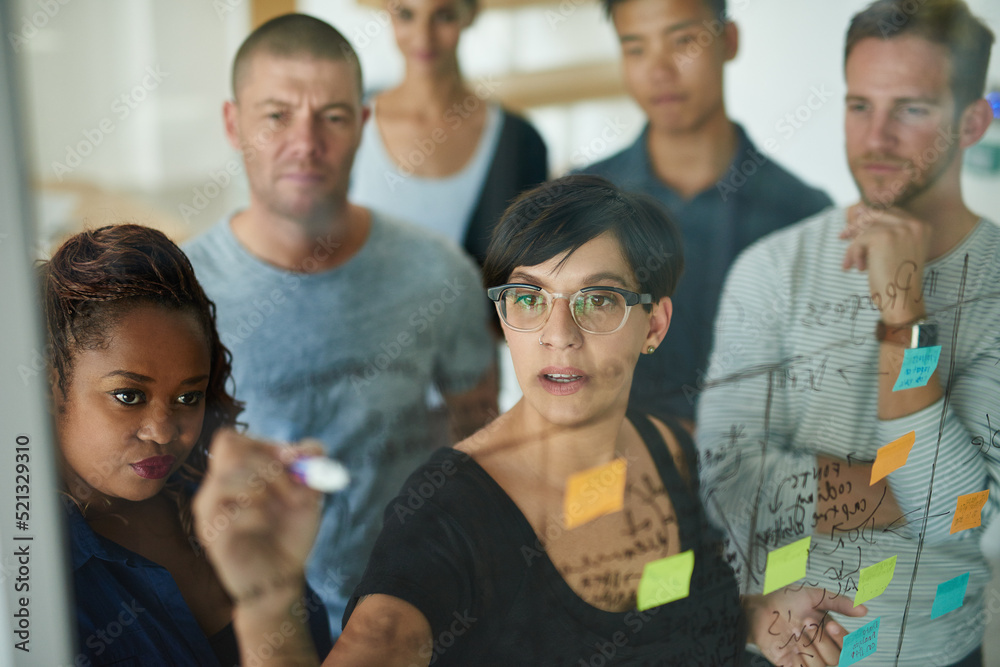 Poster Smart, thinking business people planning and writing ideas on a transparent board while working together on a group project. Busy and organized workers creating a schedule and plans with sticky notes