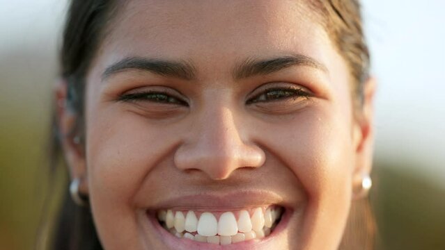 Closeup face of laughing, smiling and happy woman or volunteer looking forward with caring, friendly and kind facial expression. Portrait headshot of a carefree lady with brown eyes standing outside