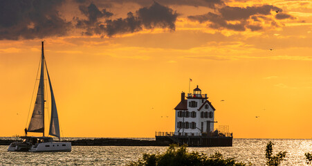 Sailboat approaches the Lorain Harbor Lighthouse on Lake Erie in the Great Lakes, at sunset.
