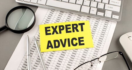 EXPERT ADVICE text written on a sticky on chart with keyboard and magnifier