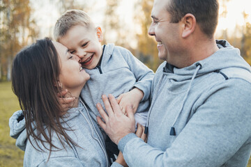 Fototapeta premium Portrait of a caucasian parents showing affection by hugging and kissing their son. Close up portrait. Happy family, childhood.