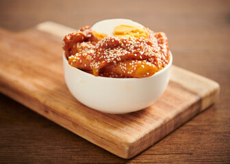 Korean rice cake stick in spicy sauce. Tteokbokki or Topokki on a wooden table. Selective focus