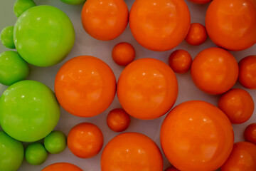 Orange and green smooth balls on the wall. Bright colored texture
