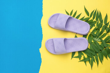 Purple flip-flops on palm leaves on a yellow-blue background. The concept of a holiday by the sea.
