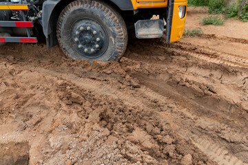 Big trucks drive on muddy roads. Liquid mud off road and there are marks of tires.