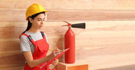 Fire safety specialist inspecting extinguisher in premises - obrazy, fototapety, plakaty