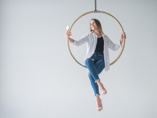 Caucasian woman gymnast on an aerial hoop takes a selfie on a smartphone. 