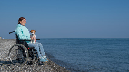 Caucasian woman in a wheelchair with a dog at the sea.
