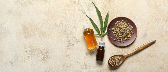 Fototapeta na wymiar Bottles of hemp oil and seeds on grunge background with space for text