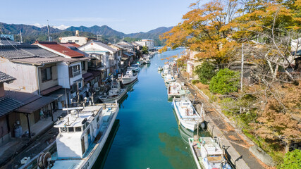 Naklejka premium 京都府舞鶴市「吉原入江」日本のヴェネチア 水路に家々が隣接する情緒豊かな街並みの空撮。京都の観光PRや自治体紹介、ノスタルジックな風景を伝える広告に最適な高品質素材です。 | Aerial view of Yoshiwara Inlet, Maizuru, Kyoto.
