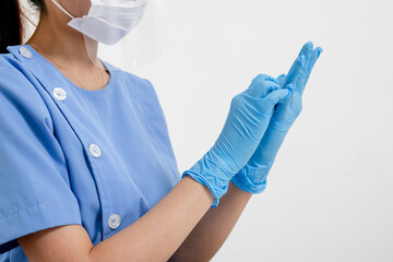Covid-19,coronavirus hand of young woman doctor or nurse putting on blue nitrile surgical gloves, professional medical safety. Vaccination, immunization or disease prevention against flu concept.