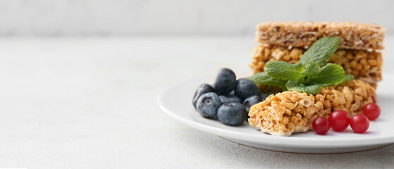 Plate with healthy cereal bars and berries on light background with space for text