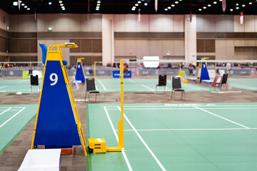 Blue chair of badminton referee with yellow colors near badminton net with blurred background in sport indoor stadium.