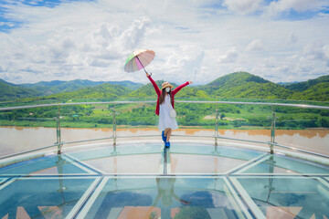 A woman stands with an umbrella on the Skywalk glass bridge as a viewpoint on the Mekong River and a new attraction between Thailand and Lao PDR.