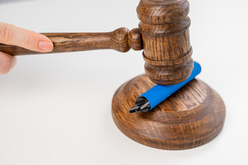 Judge hammering disposable vape with referee's gavel on white table. 