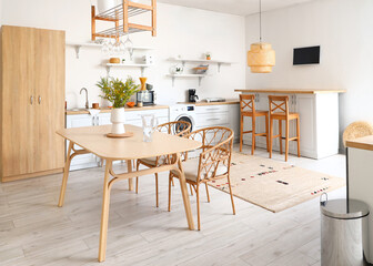 Interior of light kitchen with washing machine, counters and dining table