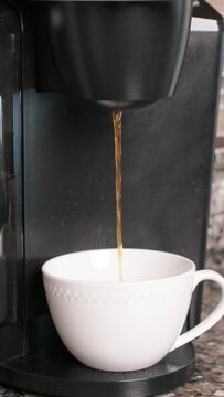 Vertical footage of the coffee machine pouring coffee in the white cup
