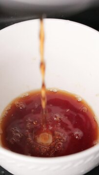 Vertical high-angle footage of the coffee machine pouring coffee in the white cup