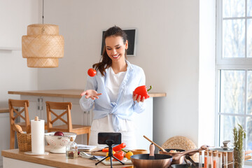 Young woman with vegetables recording cooking class in kitchen