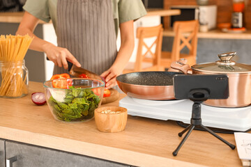 Young woman cutting onion while following video tutorial in kitchen, closeup