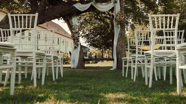 Outdoor wedding ceremony place with chiavari chairs an people getting ready