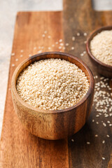 Wooden board with bowl of sesame seeds, closeup