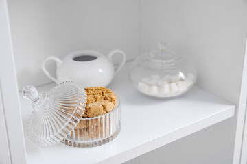 Glass bowl with cookies on shelf, closeup