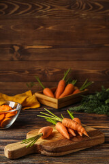 Fototapeta na wymiar Board with fresh carrots on wooden background