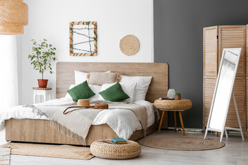 Interior of cozy bedroom with rattan poufs and mirror