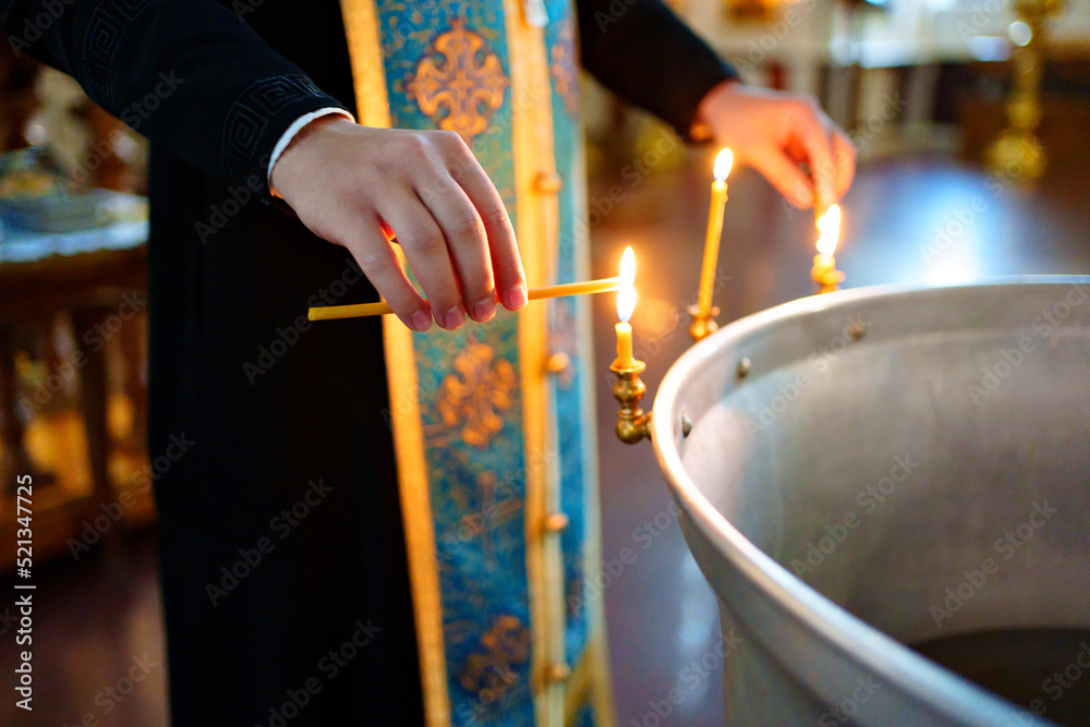 Sticker priest lights candles on the font for baptism in Orthodox Church.