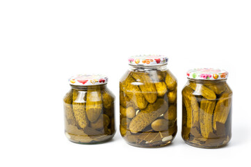 Fresh canned cucumbers in three jars, hermetically sealed with metal lids.