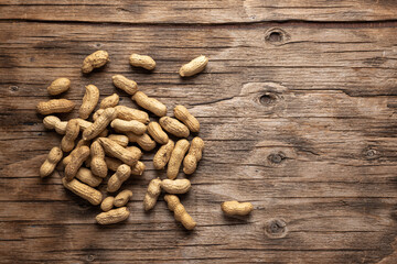 dried peanuts in pods on wooden background, top view, place for text