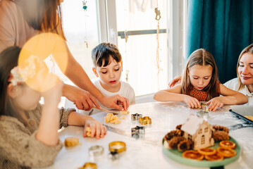 Obraz na płótnie Canvas Happy kids cooking cookies bakery together and having fun with flour indoors at cozy home on the kitchen table. Siblings in big loving family