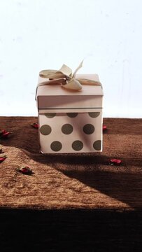 Vertical footage of a gift box with polka dot wrapping on a wooden table
