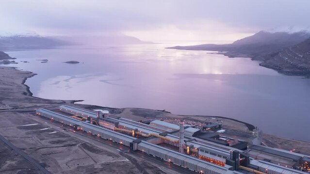Bright sunlight on horizon during cloudy morning at industrial aluminium factory, aerial