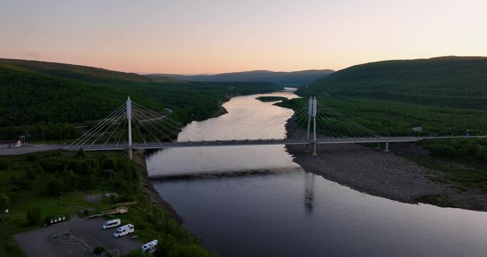 Aerial view around the Sami Bridge and Teno river, nightless night in Utsjoki, Finland - circling, drone shot