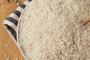  Raw round white rice in a bowl close-up on a wooden background. Healthy food.