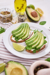 Freshly made Avocado and cream cheese toasts on a white ceramic plate and ingredients